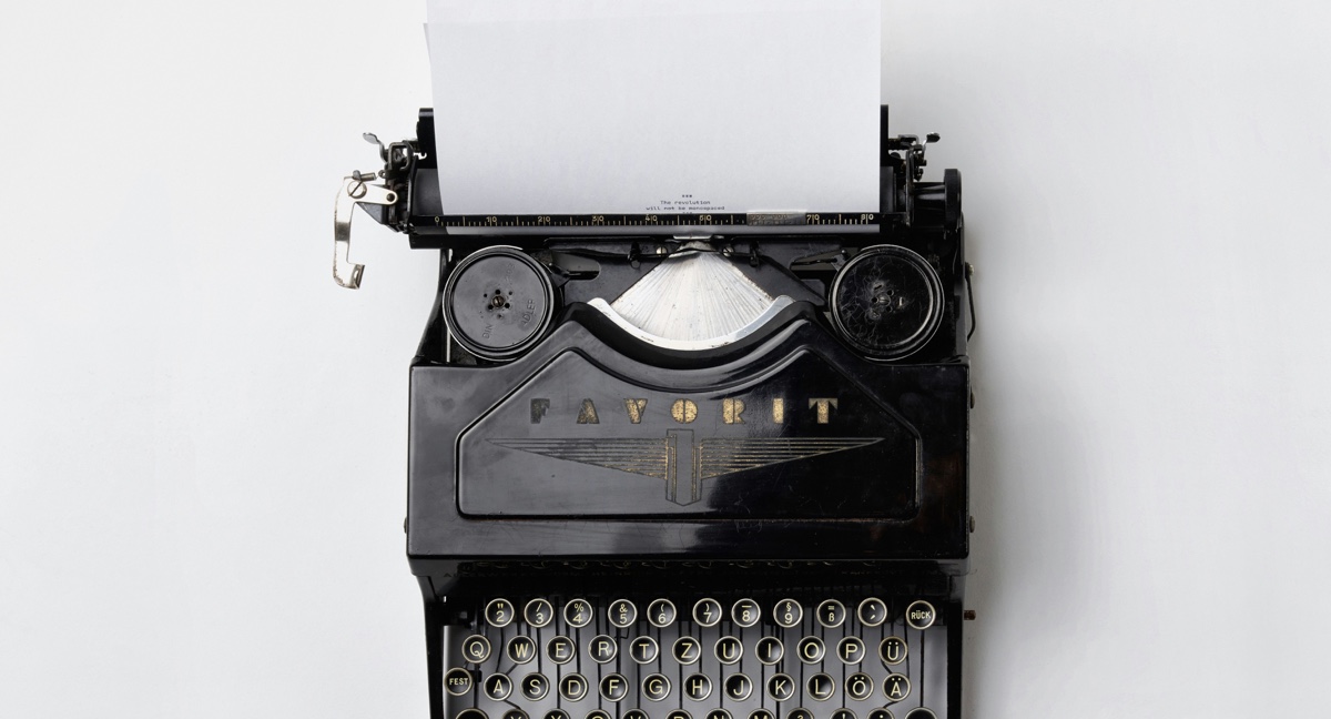 A vintage black Fayorit typewriter holding a blank sheet of paper against a white background.